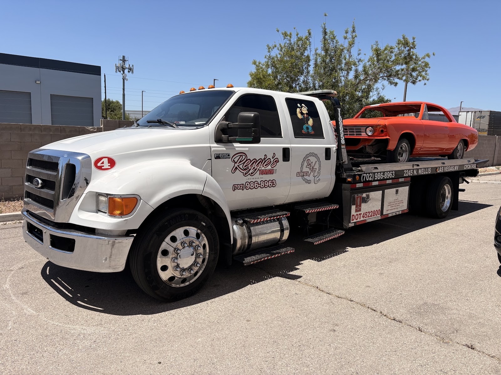 Reggie's Towing flatbed tow truck hauling an orange classic muscle car in Las Vegas
